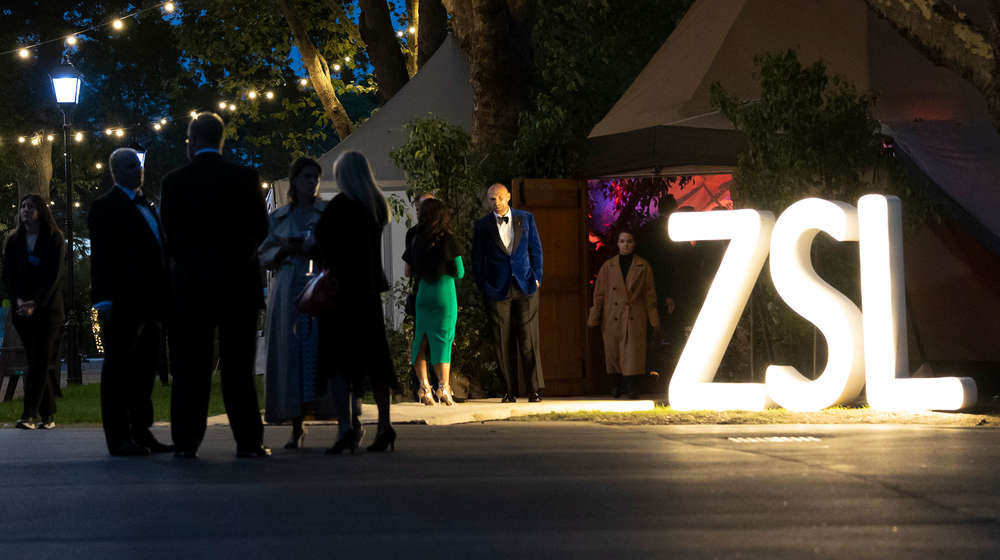 zsl sign with people wearing formal dress at night