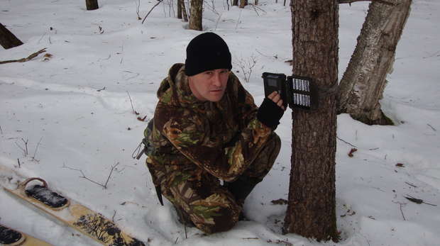 setting up a camera trap in a snowy Russian landscape