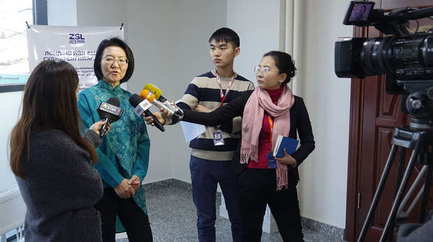 Lady talking to three journalists with microphones, on video camera