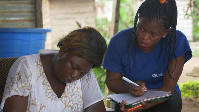 Photo - Two participants of a Village Savings and Loan Association meeting taking notes