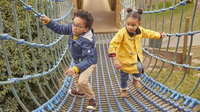 Two children on rope bridge play equipment