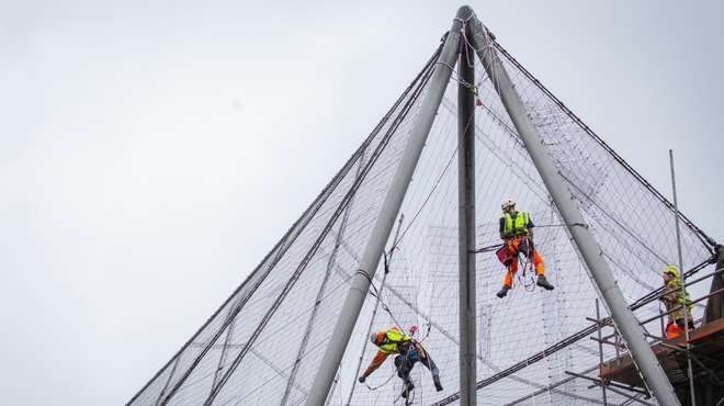 Experts abseil down the Grade II listed Snowdon Aviary to carefully peel away the first of 200 mesh panels