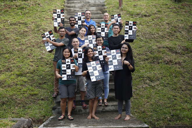 Picture of twelve people holding up posters of Asian EDGE species whilst standing on steps with a grassy backgruond