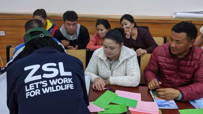 Photo - ZSL staff member (with back to camera) in a classroom with members of the community sat at desks