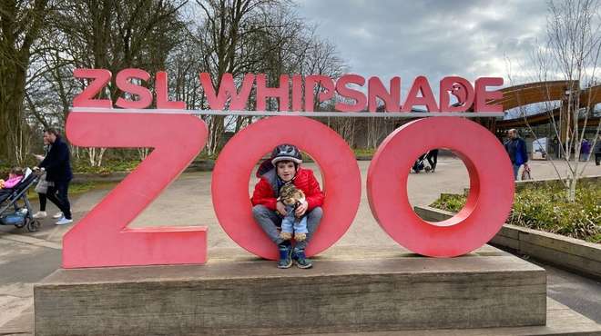Boy sits in ZSL Whipsnade Zoo sign