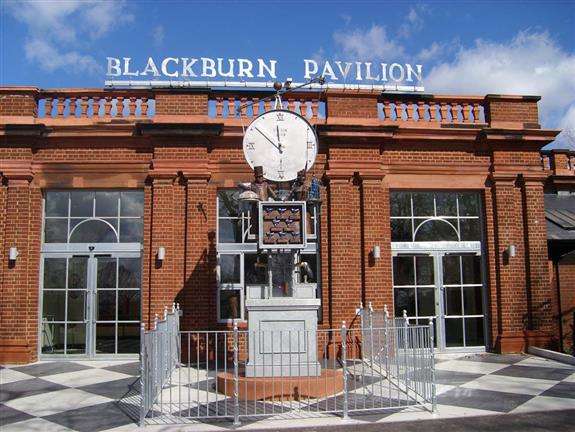 A large metal clock with moving parts outside the Blackburn Pavilion