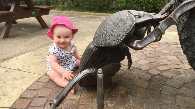 baby with giant stag beetle sculpture
