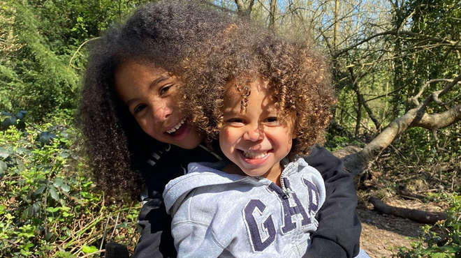 two kids with curly hair smiling