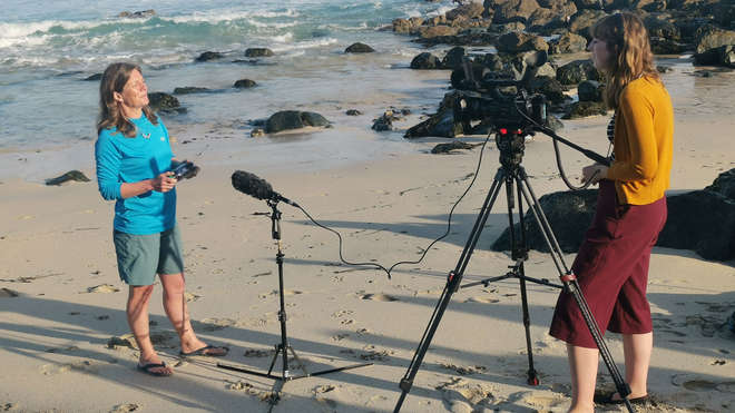 woman on beach talking to cameraman