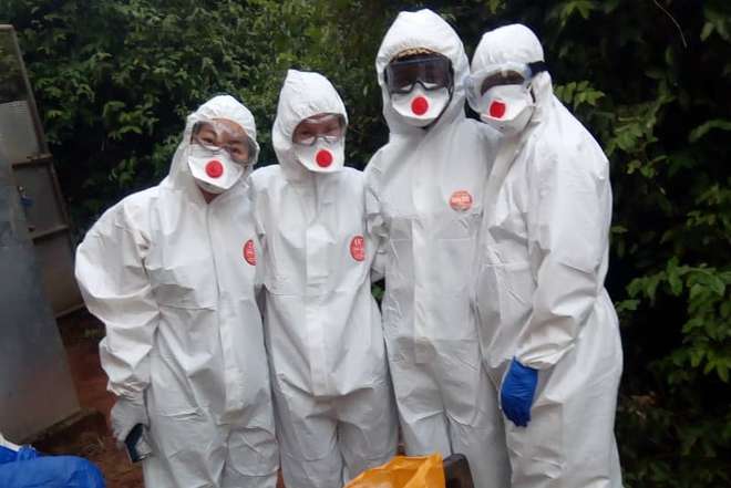 Louise and Rosa with Ghanaian colleagues, wearing white protective outfits, goggles and face masks.